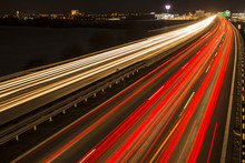 Night Scene Of Motion Blurred Light Tracks Glowing To The Darkness Of Highway Traffic To The City Just After Sunset. Creative Long Time Exposure Diagonal Composed Photography.