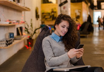 Cute brunette woman with phone in modern workplace.