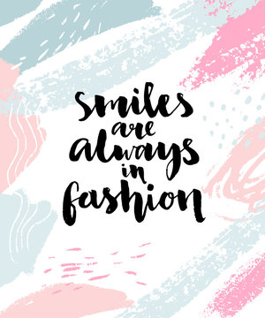 Smiles are always in fashion. Inspirational calligraphy quote on abstract brush strokes background