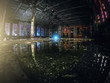 © DedMityay - Large empty abandoned warehouse building or factory workshop at night with reflection in water, abstract ruins background