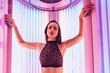 © mnelen.com - an attractive young girl in a fashionable swimsuit sunbathing in a vertical sunbed under the ultraviolet rays