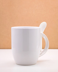 Wall Mural - White coffee mug and spoon on backdrops. Ceramic tea cup for your design.