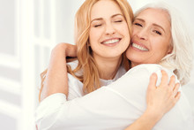 Happiness Is Homemade. Sunshiny Mature Daughter And Her Elderly Mom Grinning Broadly Into The Camera While Embracing And Enjoying A Happy Family Moment Spent Together.