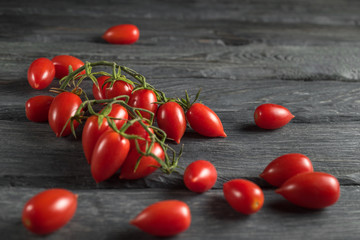 View at a black wooden table with a branch of tomatoes.