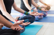© uv_group - Group of sportive adult people doing lotus pose, yoga class practice and exercise concept. Meditation, breathing, peace and quiet at hatha yoga training with coach. Close up on hands mudra