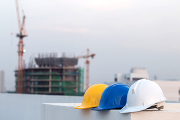 Wall Mural - Group of safety helmet and the blueprint at construction site with crane background