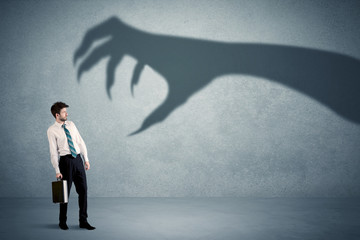 Wall Mural - Business person afraid of a big monster claw shadow concept on background