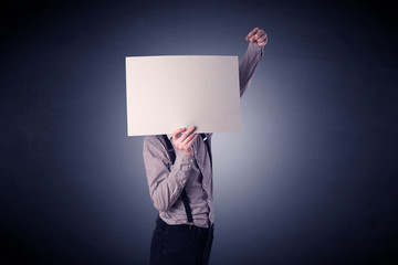 Young businessman hiding behind a blank piece of paper