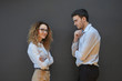 © Anatoliy Karlyuk - Sideways portrait of attractive positive young female office worker with voluminous hair wearing stylish glasses crossing arms on her chest while posing at blank wall with her bearded male coworker
