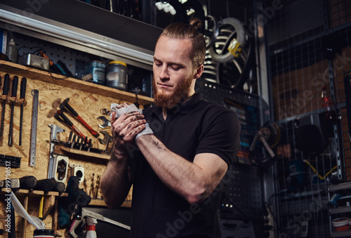 Fotografía Handsome stylish redhead worker, cleaning his dirty hands after repairing working in a workshop