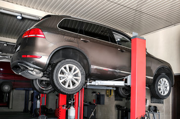 Car on hydraulic vehicle lift in garage. Tire service