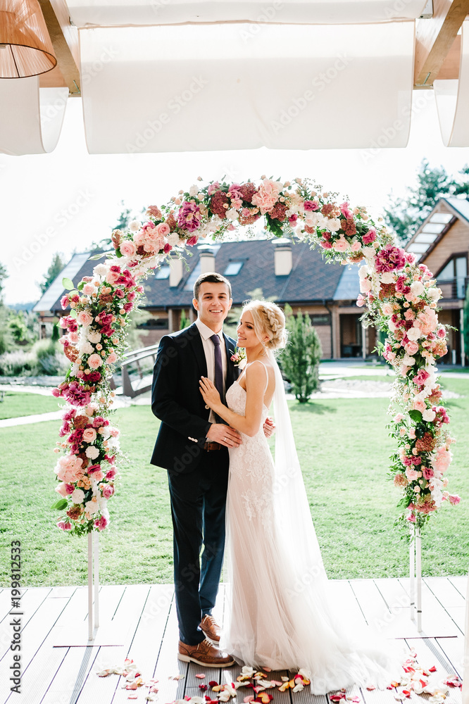 Happy bride and groom standing after wedding ceremony under the arch ...