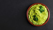 Guacamole spread  in clay bowl on a black background. Avocado sauce. Top view with copy space.