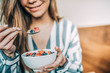 © DavidPrado - Crop woman close up eating oat and fruits bowl for breakfast