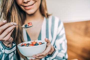 Wall Mural - Crop woman close up eating oat and fruits bowl for breakfast