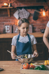 Sticker - Little girl standing with bowl of cooked salad on kitchen table.