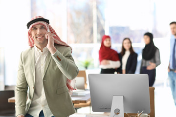 Poster - Muslim businessman in traditional clothes talking on phone at workplace