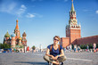 Beautiful young female student sitting on a paving stone on Red Square in Moscow, traveling to Russia
