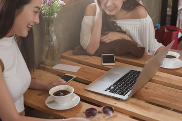 Two teenage women meet in coffee shop use smartphone and laptop play social media together in afternoon, life style of new teenager