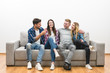 © realstock1 - The four happy friends sit on the sofa on a white wall background