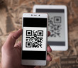 © yurich84 - Man hand scanning qr code from the tablet using mobile phone.