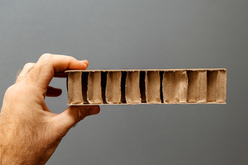 Factory worker male hand inspecting against gray background a corrugated cardboard carton paper for packing 