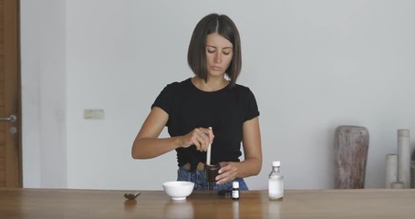 Wall Mural - Young pretty woman makes toothbrush independently from ecological natural materials at home. Girl stirring ingredients in a jar. Zero waste concept 4k