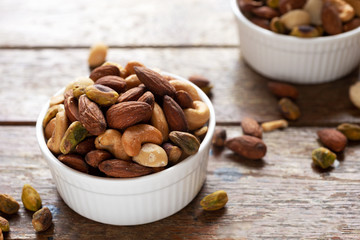 Poster - cashews, almonds pistachios, macadamia, mixed nuts healthy snack in white ceramic bowl on  wooden table background