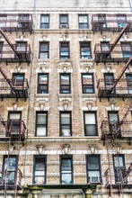 Old Apartment Condo Building Exterior Architecture In Chelsea, NYC, Manhattan, New York City With Fire Escapes, Windows, Ladders