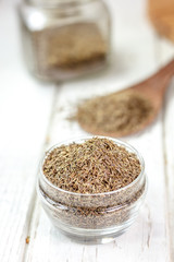 Sticker - Cumin or caraway spice in a glass jar over white wooden background.