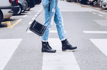 Fashion Blogger Outfit Details. Fashionable Woman Wearing Ripped Vintage Denim Jeans, Suede Jacket, Black Biker Boots -ankle Shoes And Black Trendy Handbag. Detail Of A Perfect Fall Fashion Outfit. 