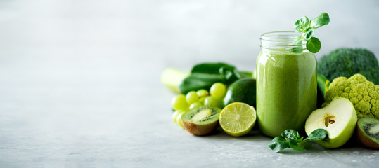 glass jar mugs with green health smoothie, kale leaves, lime, apple, kiwi, grapes, banana, avocado, 