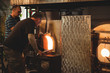 © Wavebreak Media - Team of glassblowers heating a glass in furnace