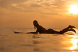 Surfer girl in ocean at sunset time