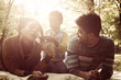 © Mladen - Happy African American parents lying down in nature and talking with little daughter