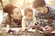 © Mladen - Young African American parents in park with daughter using mobile phone together.