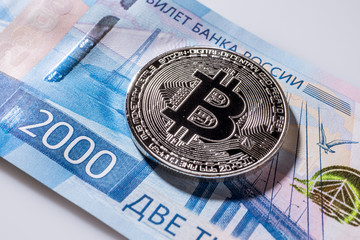 One Bitcoin on Russian banknotes. Closeup, macro shot. Banknote of two thousand rubles. 2000 rub. Papermoney, cash.