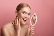 © Yakobchuk Olena - Portrait of groomed and naked girl with looking glass in hand. She is staring at camera with joy. Copy space in right side. Isolated on rose background