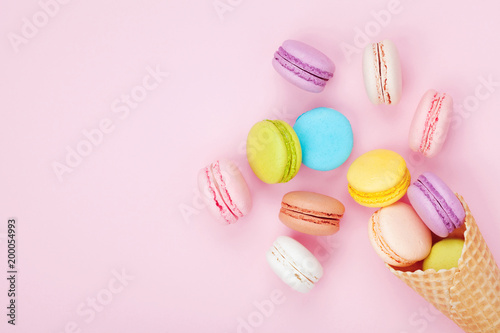 Fotomural Waffle cone with colorful macaron or macaroon on pink pastel background top view
