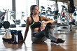© Kitreel - A fit young woman (girl) sits on the floor of a gym while waits between an exercise and the other