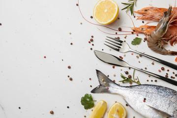 Wall Mural - Shrimps and fish with spices and silverware isolated on white