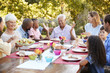 © Monkey Business - Family and friends talking over lunch at a table in garden