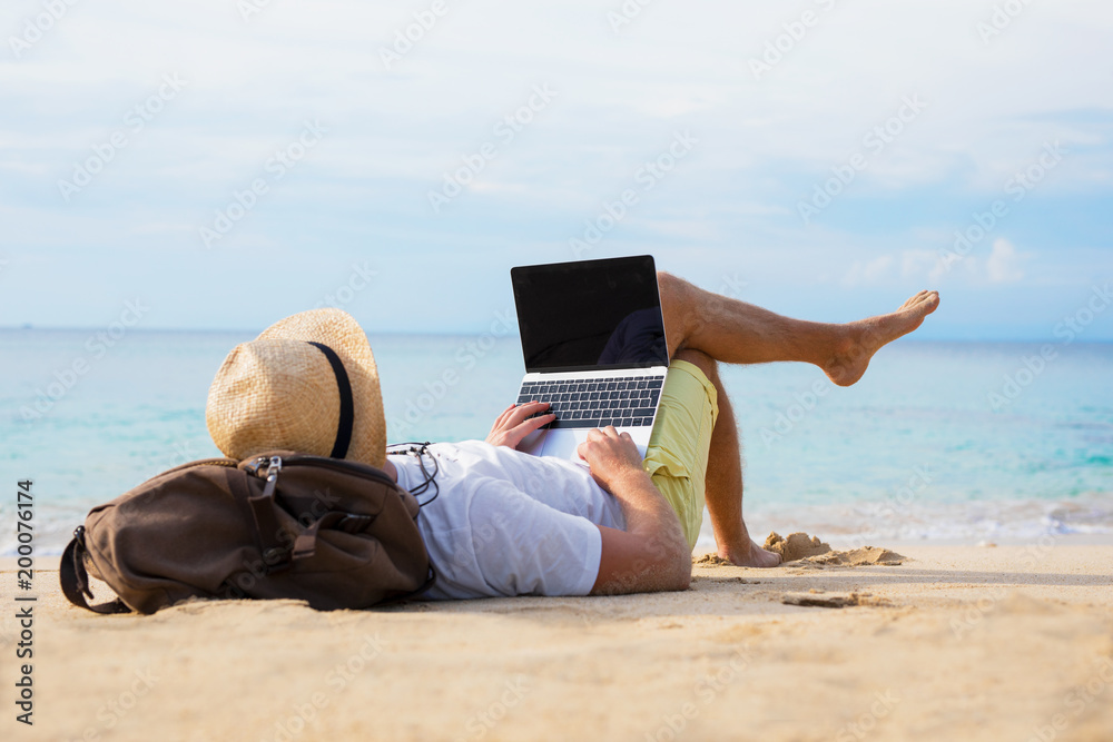 Relaxed man with laptop on the beach - obrazy, fototapety, plakaty 