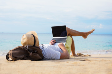 relaxed man with laptop on the beach