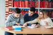 © Aleksandr - University students sitting together at table with books and laptop. Happy young people doing group study in library
