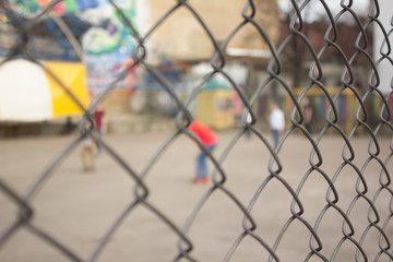 Unfocused children play behind fence