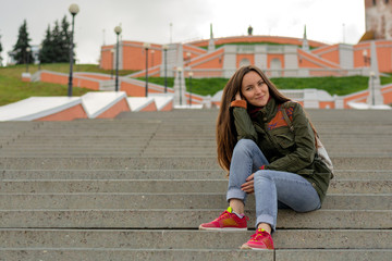 Wall Mural - Young cheerful woman sitting on steps on a spring day