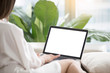 © fizkes - Woman on sofa working on laptop with mockup blank screen. Empty copyspace on monitor for  advertisement, language learning ad, online shopping website, social media site. Close up, focus on screen.