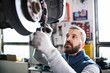 © Halfpoint - Man mechanic repairing a car in a garage.