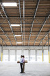 © Mint Images - Caucasian man and black female holding cardboard boxes in middle of empty warehouse interior.